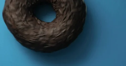 Chocolate pecan donut close-up macro shot spinning on a blue background Stock Footage 78068514