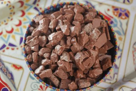 Chocolate pieces in a bowl on a patterned table Stock Photos