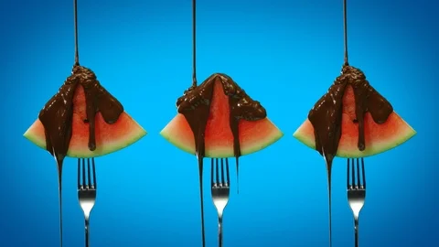 Chocolate pouring over watermelon triangular slices on blue background 스톡 동영상 125611674