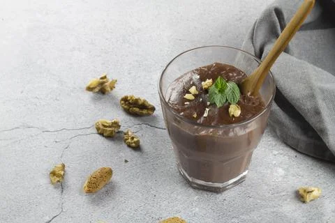 Chocolate pudding with mint and walnuts on a concrete background. Stock Photos