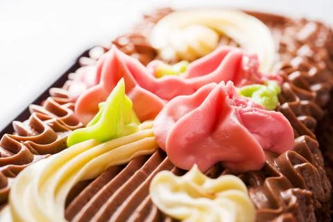 Chocolate rectangular cake decorated with cream roses on a light table. Swe.. Foto stock