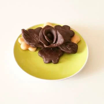 Chocolate roses on green plate Stock Photos