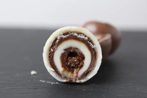 Chocolate round candy sphere with layered white and dark chocolate in section Stock Photos
