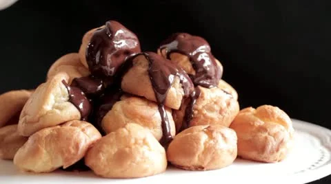 Chocolate sauce being poured over profiteroles Vídeos de archivo 24673469