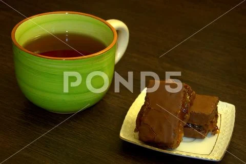 Chocolate sponge cake on a white porcelain plate and a cup of tea. Stock Photos