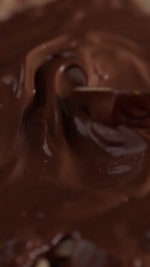 Chocolate spreading with spoon over hazelnuts Stock Footage 332084576