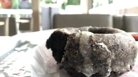 Chocolate Sugar Glazed Donut with a Bite on a table Stock Footage 215484923