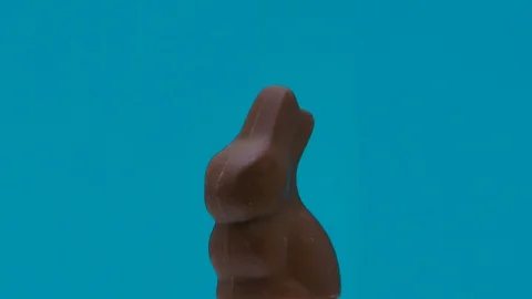 Chocolate syrup dripping on Easter bunny rotating on coloured backdrop Stock Footage 127857264