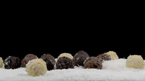 Chocolate truffles falling in coconut flakes on black Stock Footage 133872007