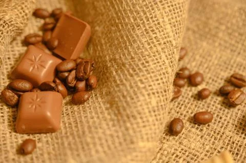 Chocolates and coffee beans on a background of rough homespun fabric. Close u Stock Photos