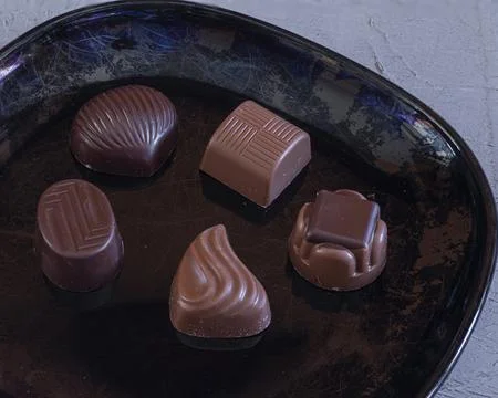 Chocolates filled with various assorted flavors on a black plate Foto stock