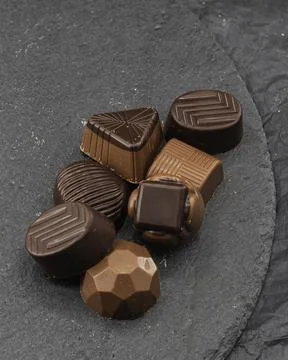 Chocolates filled with various assorted flavors on a stone plate 스톡 사진
