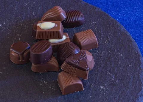 Chocolates filled with various assorted flavors on a stone plate 写真素材