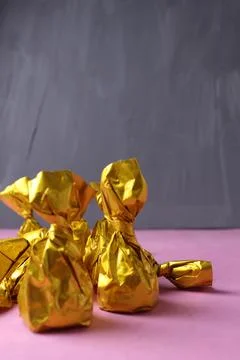 Chocolates on a gray background close-up. Sweets in a golden yellow wrapper Stock Photos
