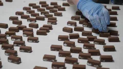 Chocolates move along a conveyor line and are manually controlled at the factory 库存影片 146161595