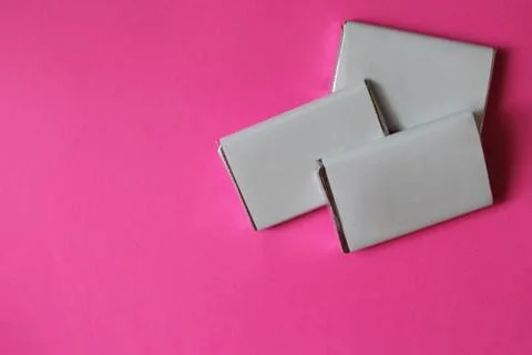 Chocolates wrapped in silver foil and white blank paper isolated on pink surf Stock Photos