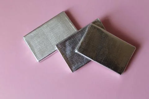 Chocolates wrapped in silver foil isolated on pink surface Stock Photos
