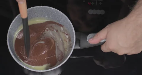 Chocolatier mixing melted liquid dark and white chocolate with silicone spatula Stock Footage 250232298