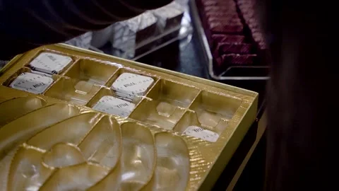 A chocolatier placing white shiny gelatin-coated chocolate with writings inside Vidéo 278489341