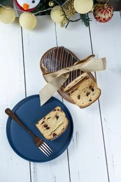 Chocotone slice on a plate, next to a fork, ribbon bow and a Christmas tree.. Stock Photos