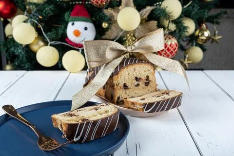 Chocotone slice on a plate, next to a fork, ribbon bow and a Christmas tree. Stock Photos