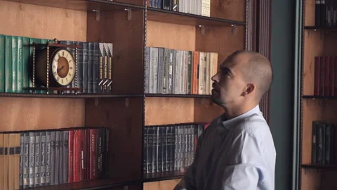 Choice and decision concept. Man makes choice standing in library. A man chooses Stock Footage 99377012