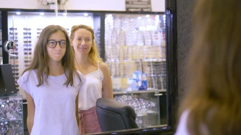 Choice of frames for glasses in optics. Mom and her teenage daughter choose a Stock Footage 115371975