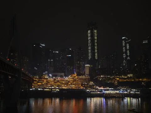 The Chongqing riverfront skyline glowing at night with a lit bridge, China Stock Photos