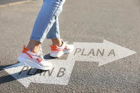 Choosing between Plan A and Plan B. Woman near arrows on road, closeup view Foto stock