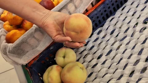 Choosing the perfect peach at the grocery store Stock Footage 345485434