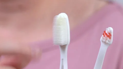 Choosing toothbrush, advantages, rigidity. Hand holding two different brushes Stock Footage 245772779