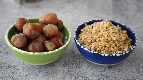 Chopped and roasted hazelnuts are shown in a blue bowl, alongside whole Stock Footage 337285583