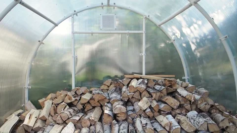 The chopped and sawn trunks of trees is stacked in a large log woodpile in room. Stock Footage 128902797
