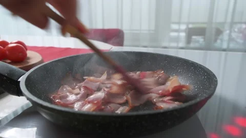 Chopped bacon are fried in a hot frying pan Stock Footage 131785550