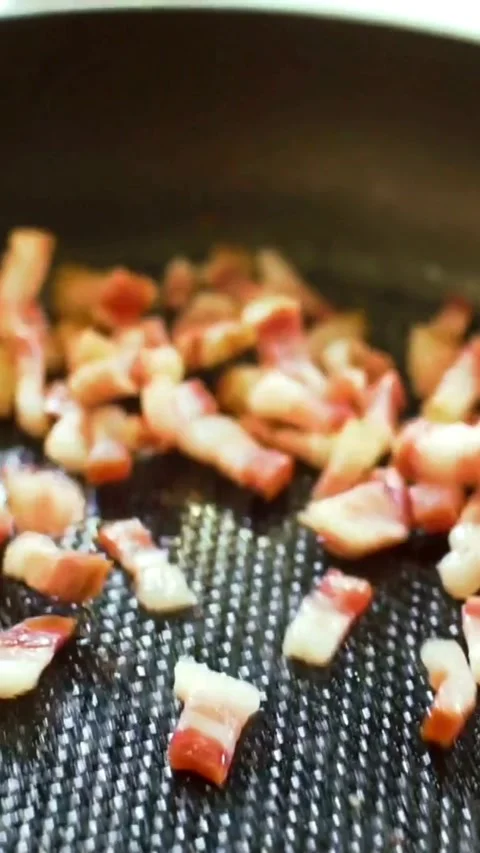 Chopped bacon cubes frying in hot pan with oil Stock Footage 334170296