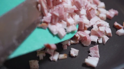 Chopped bacon is placed in a hot pan in slow motion Stockbeeldmateriaal 96420211
