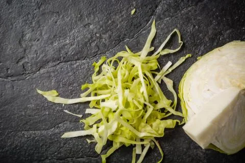 Chopped cabbage on a black stone background. Foto stock