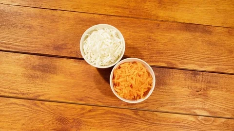 Chopped carrot and cabbage in white cup on wooden background close up. Stock Footage 74396991