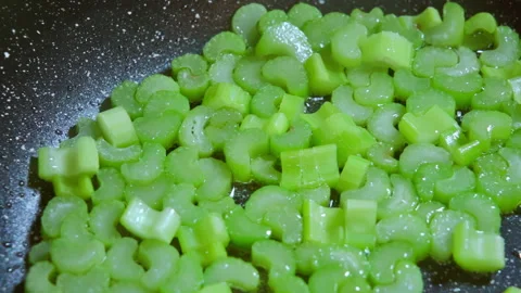 Chopped celery stalks are fried in a pan in hot olive oil. Slow motion 100fps. Stock-Footage 296156771
