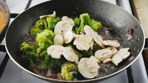 Chopped champignons fall into the onion with broccoli fried in a pan Stock Footage 244543948