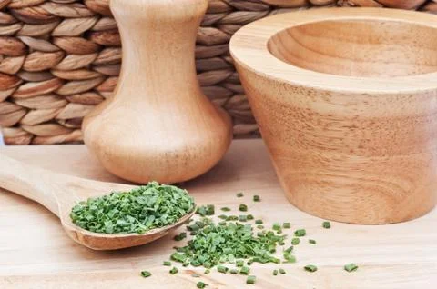 Chopped chives in rustic kitchen setting with wooden pestle and mortar Foto stock