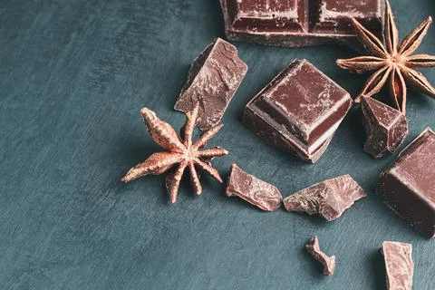 Chopped chocolate cubes and star anise on dark background with copy space Stock Photos