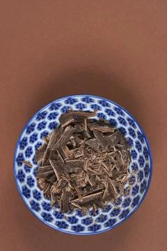 Chopped dark chocolate in a blue patterned bowl on brown background Stock Photos