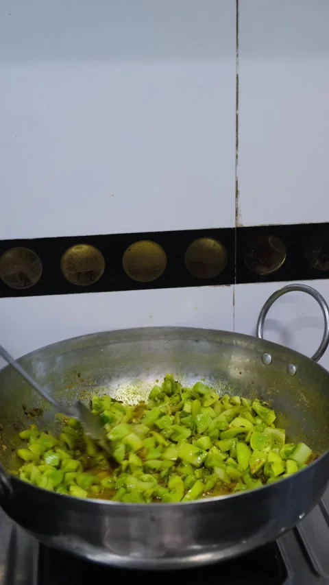 Chopped green tomatoes being cooked with spices in steel pan on gas stove Video stock 331898835