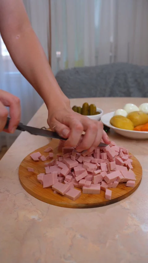 Chopped ham pieces on round board with fresh ingredients nearby Stock Footage 329059869