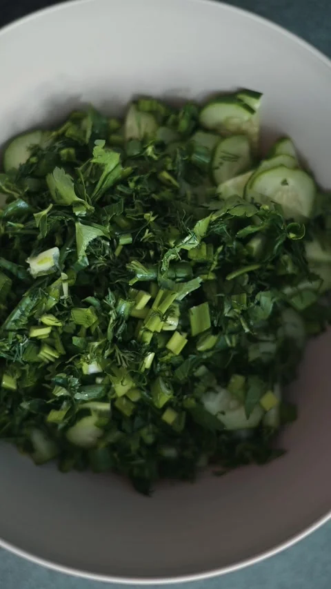 Chopped leafy greens are mixed together in a large bowl. The preparation takes Видео 338304180