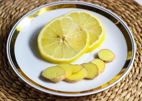 Chopped lemon and ginger root on a saucer. Stock Photos