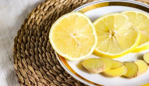 Chopped lemon and ginger root on a saucer. Stock Photos