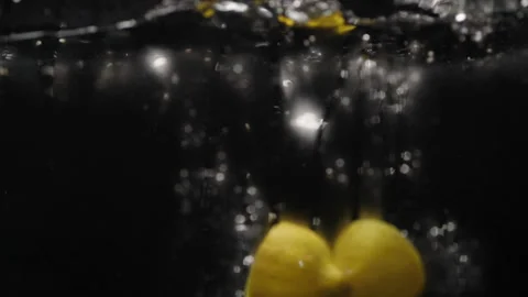 Chopped Lemons falling into water in slowmotion Stock Footage 254587118