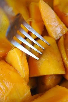 Chopped mango pieces with a fork on a small plate Stock Photos